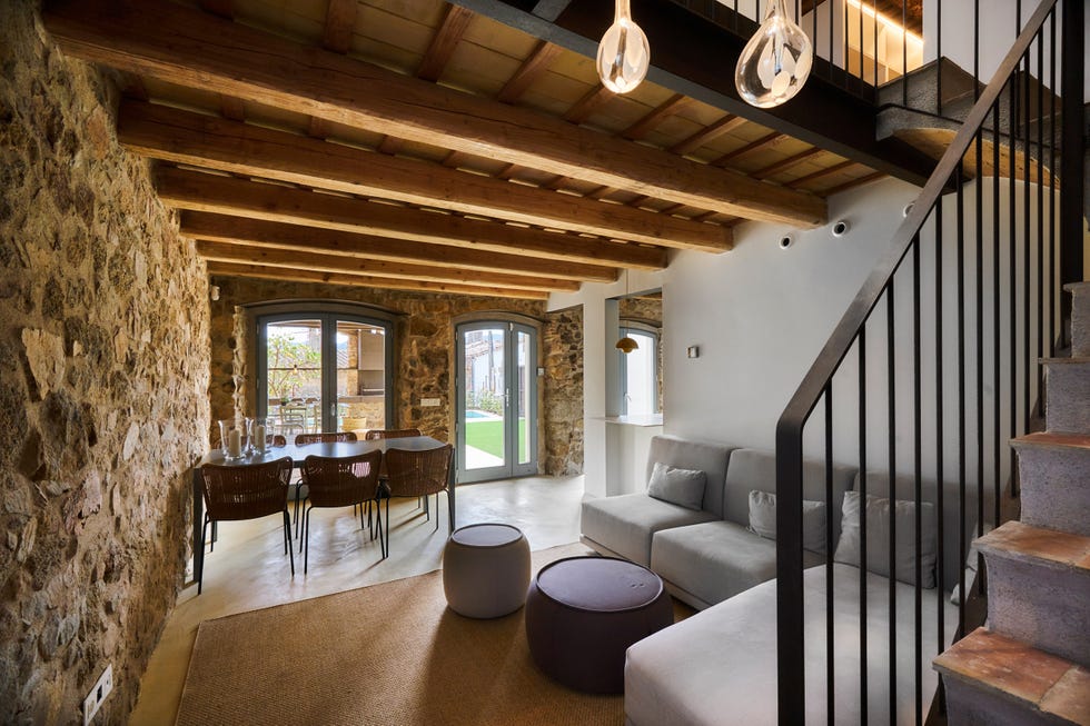 salón comedor abierto a la cocina con paredes de piedra y vigas de madera