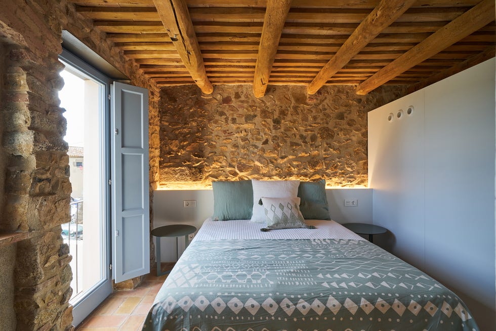 dormitorio rústico con paredes de piedra y vigas de madera vistas
