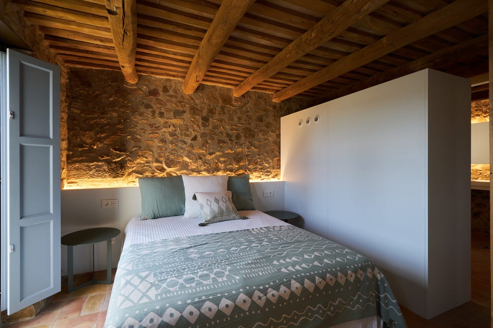 dormitorio rústico con paredes de piedra y vigas de madera vistas