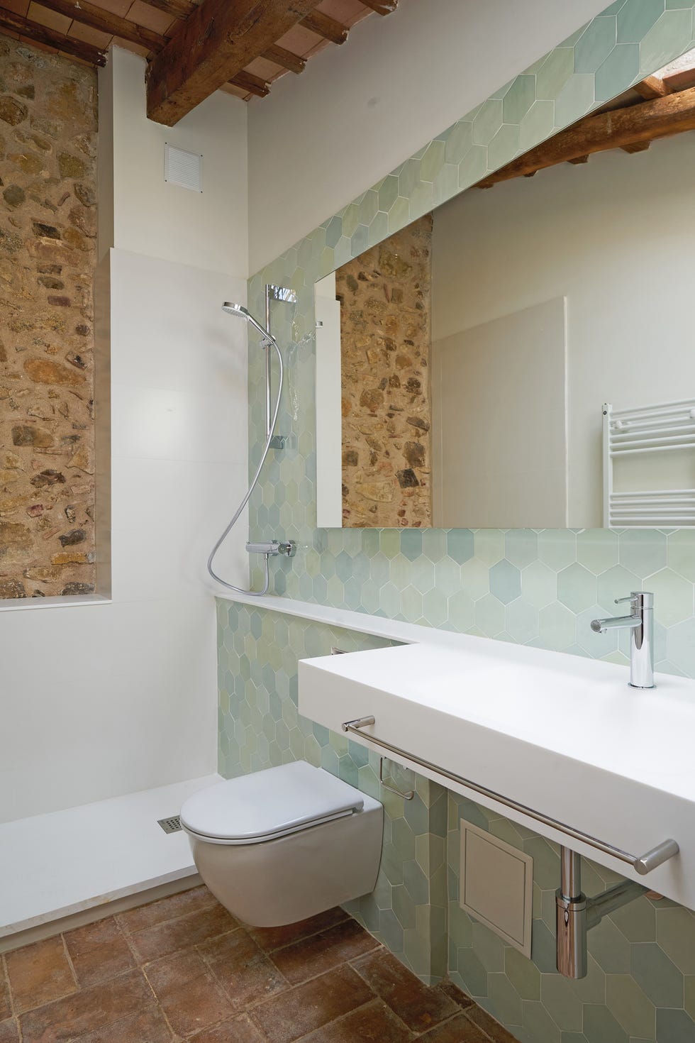baño con ducha y paredes de azulejos hexagonales azules