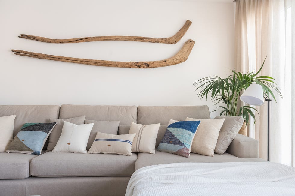 sofá gris con chaise longue y pieza decorativa de madera en la pared
