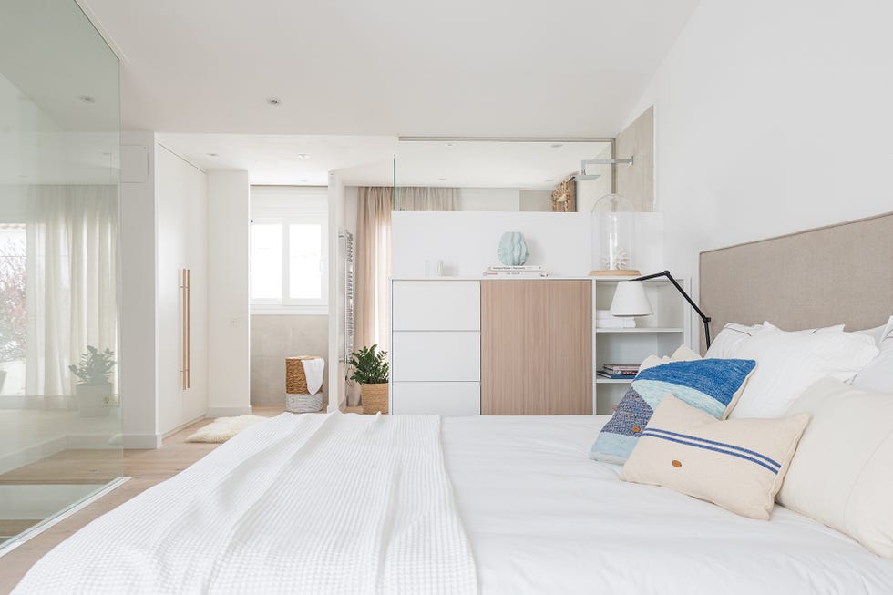 dormitorio con baño en suite decorado en color blanco con muebles de madera