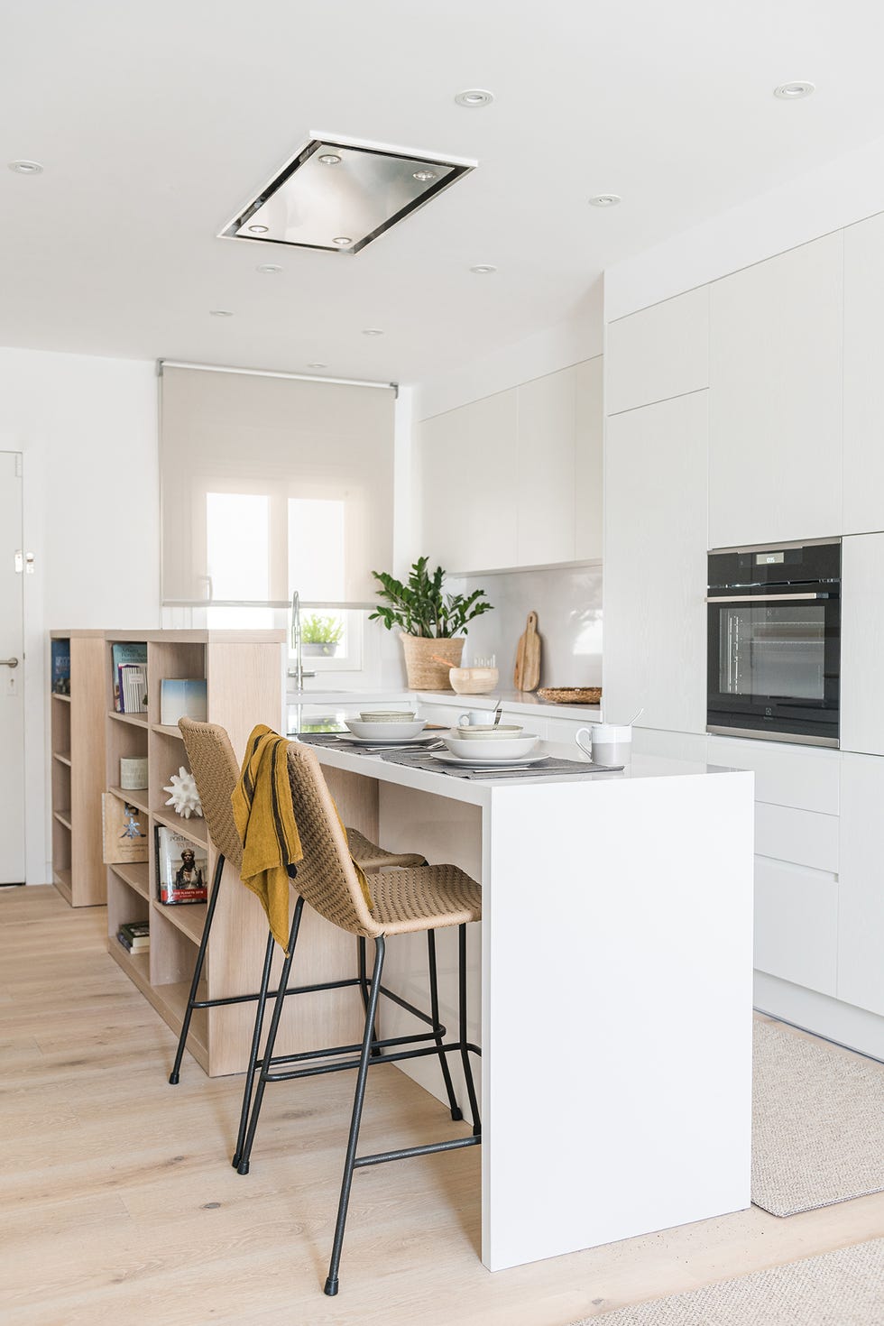 cocina abierta diseñada en blanco con barra de desayunos y taburetes de fibras