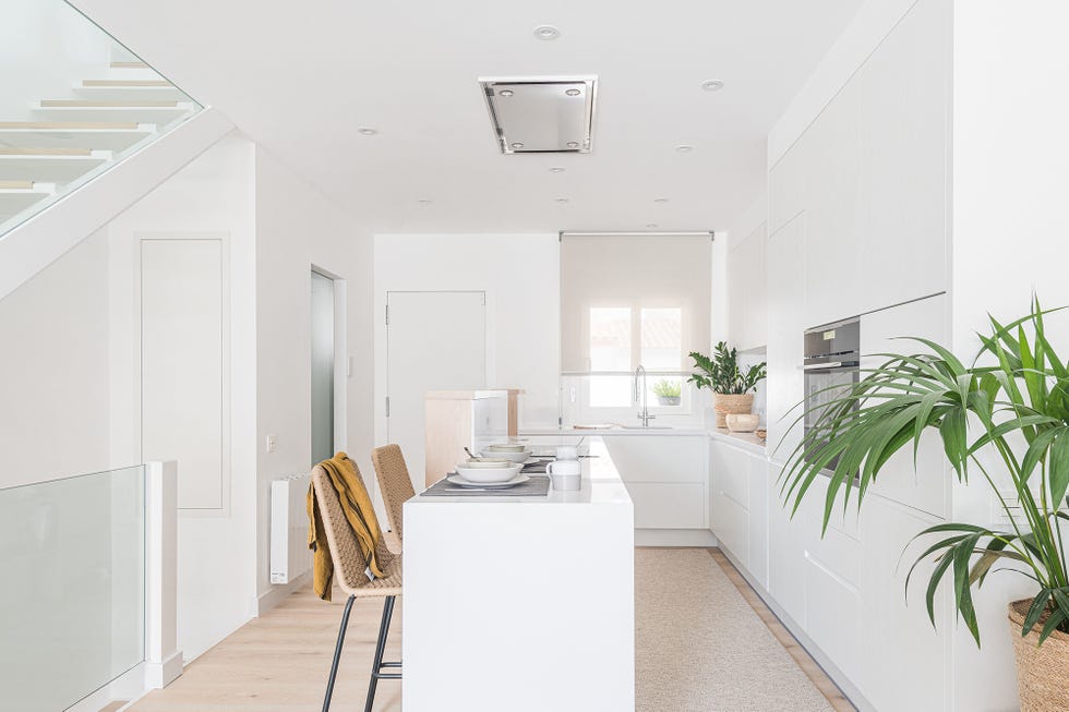 cocina abierta diseñada en blanco con barra de desayunos y taburetes de fibras