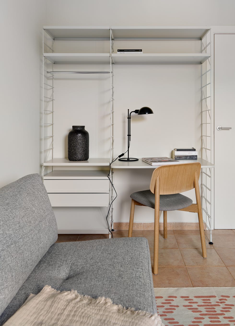 sofá cama gris y estantería blanca con escritorio
