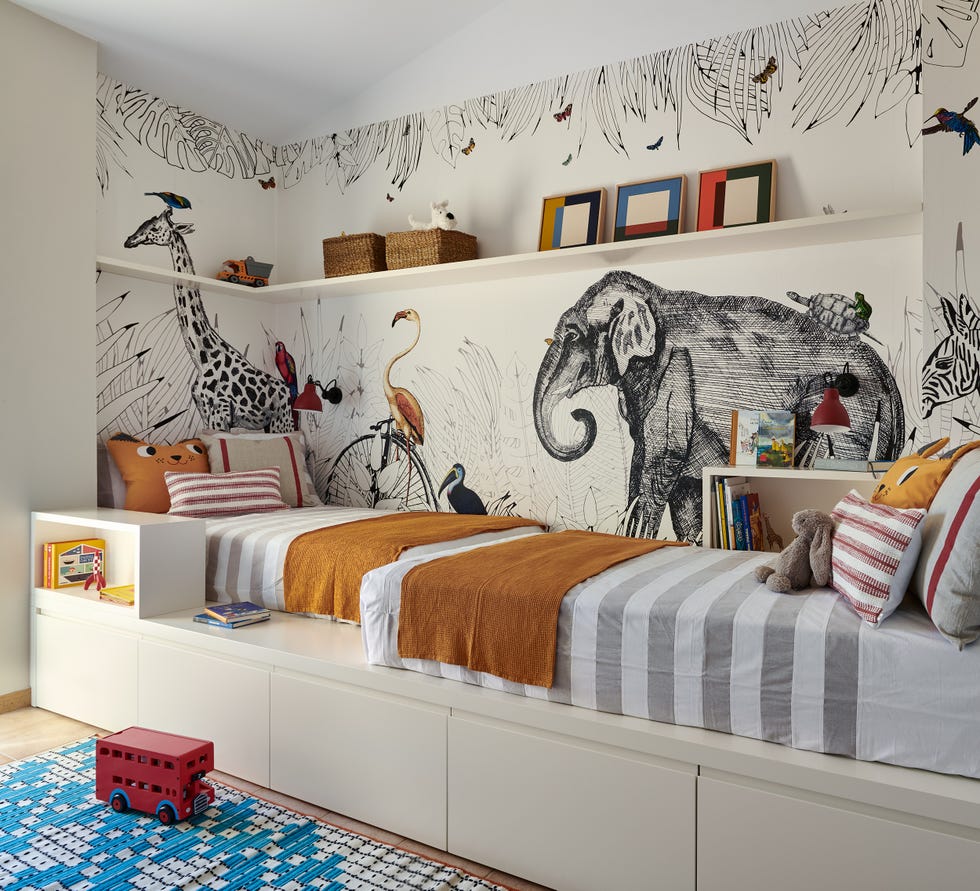 habitación infantil con dos camas sobre una tarima y papel pintado con dibujos de animales