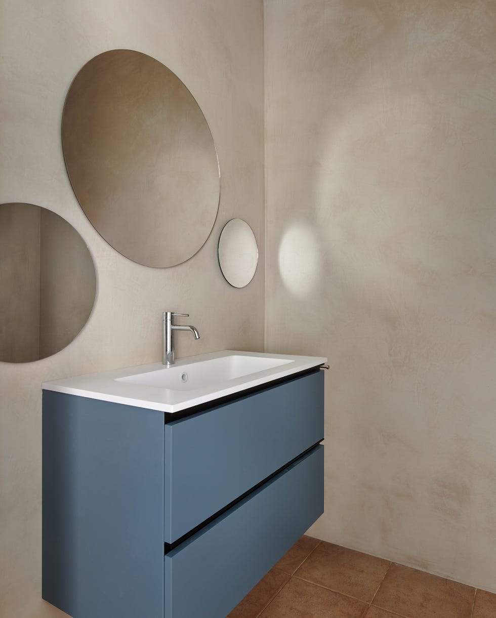 baño con mueble volado azul y espejos redondos
