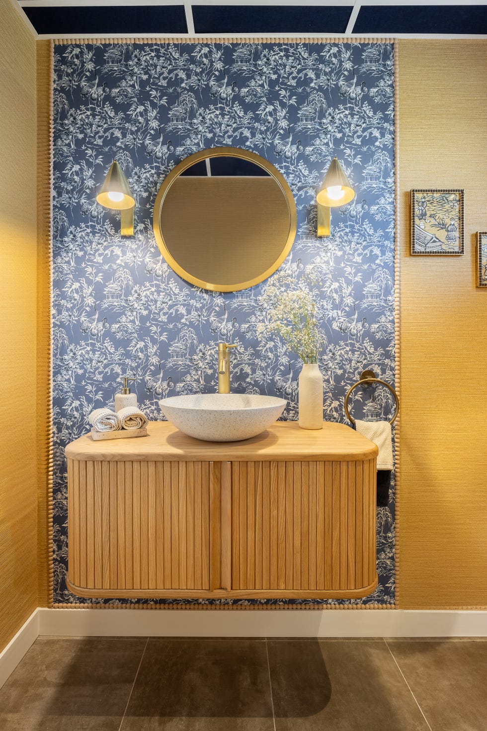 baño con mueble de madera volado y papel pintado floral azul