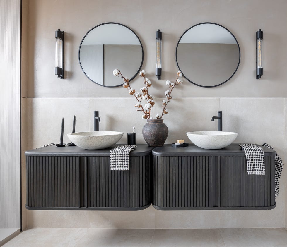 baño con dos muebles volados con espejos redondos