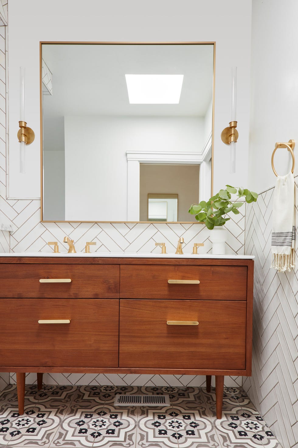 baño con suelo hidráulico, mueble de lavabo de madera mid century, grifos de latón y pared con azulejos en espiga