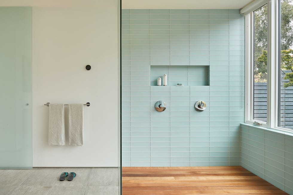baño con ducha a ras de suelo, azulejos turquesas y suelos de madera y cemento pulido