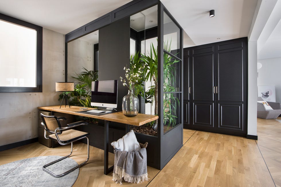 despacho abierto con escritorio de madera junto a un jardín interior
