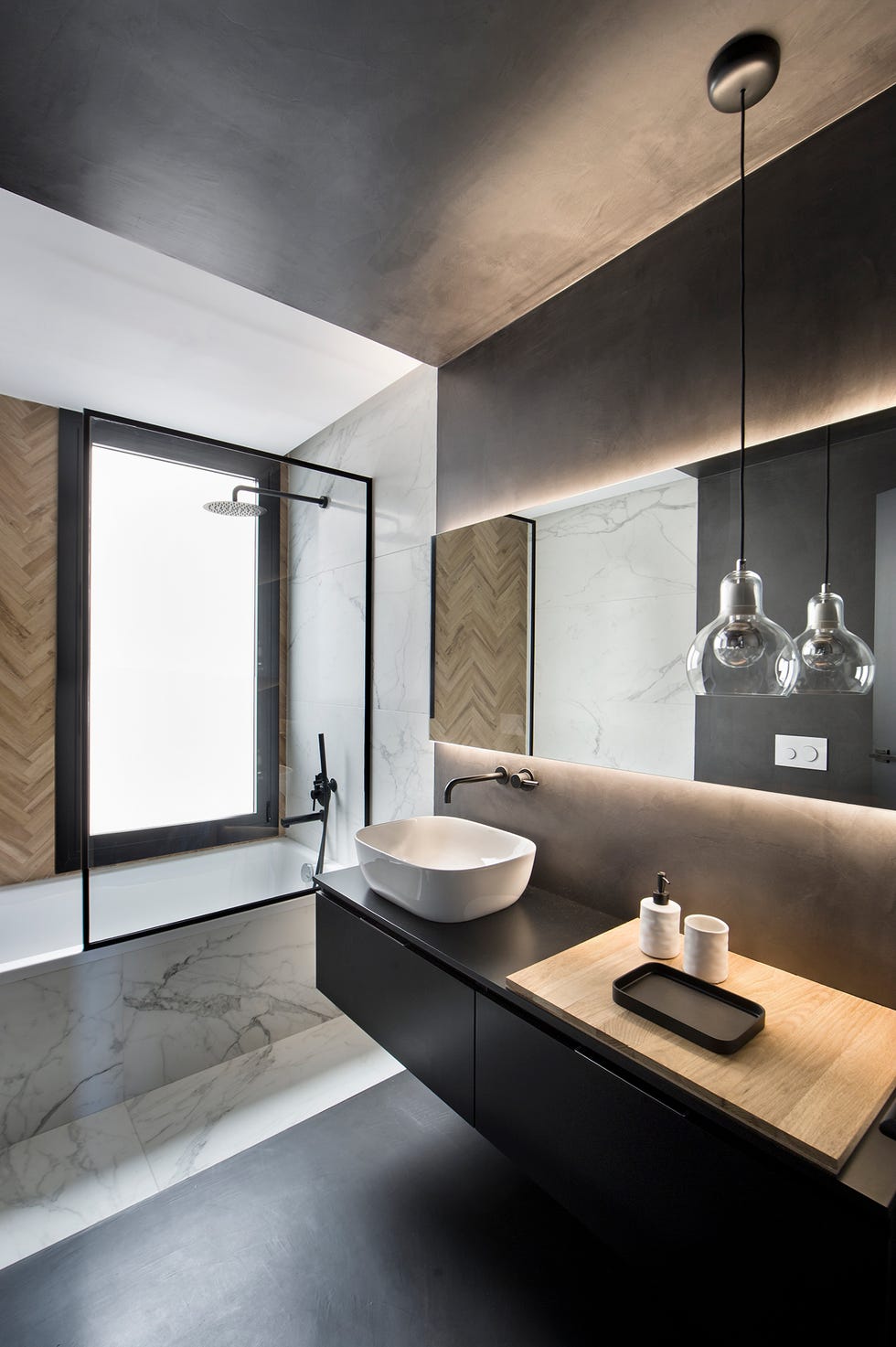 baño de diseño moderno con microcemento negro y bañera revestida en mármol