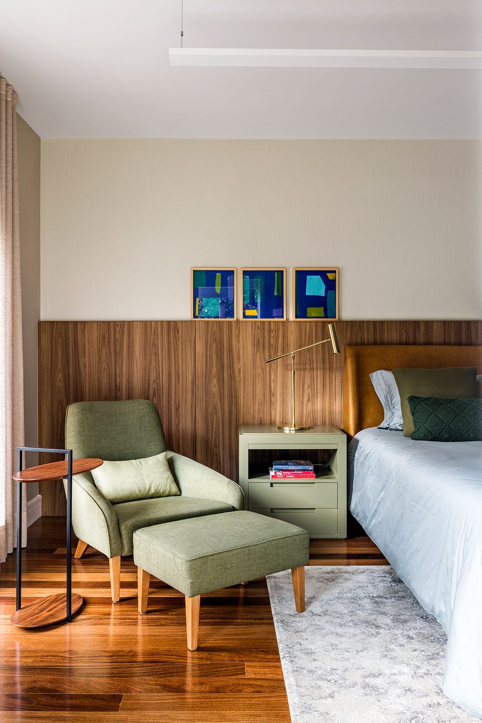 dormitorio con cabecero de madera y butaca verde con reposapiés a juego