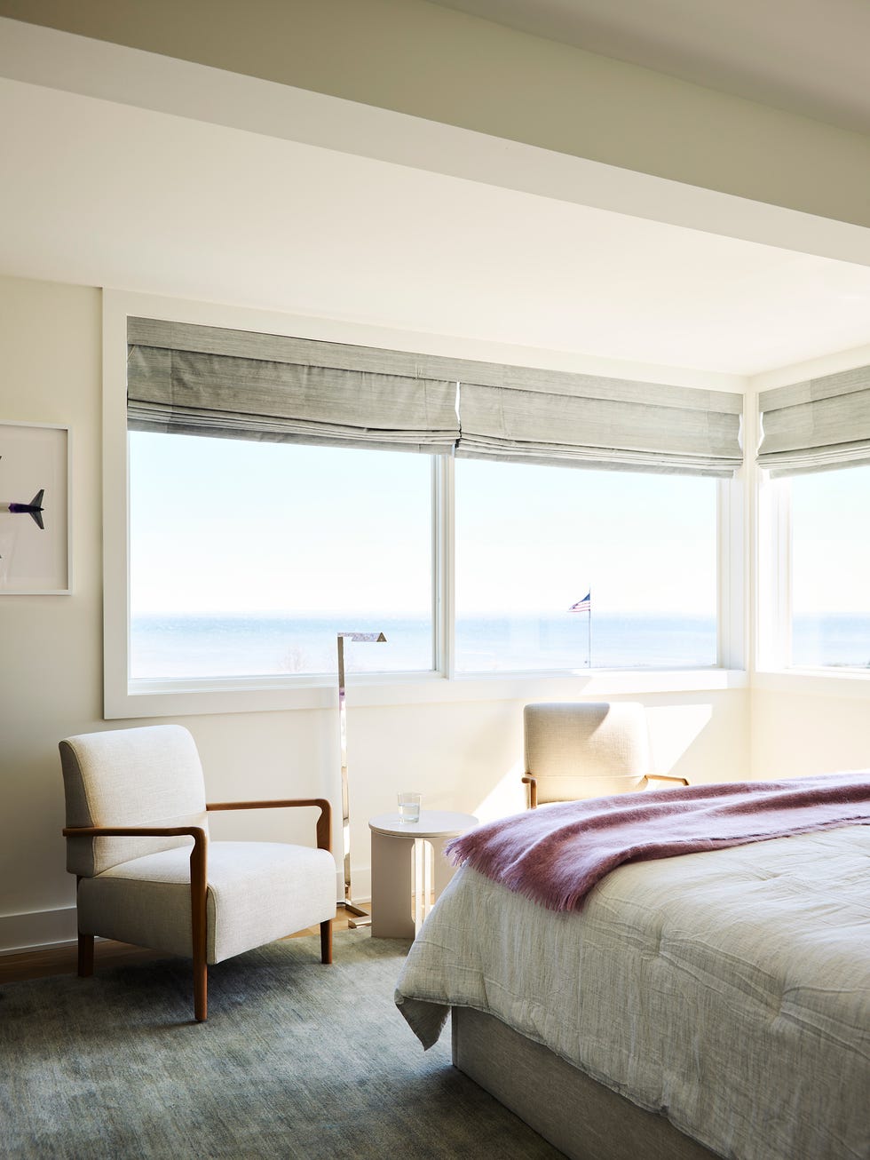 dormitorio de diseño contemporáneo con cama tapizada en gris y dos butacas blancas a los pies