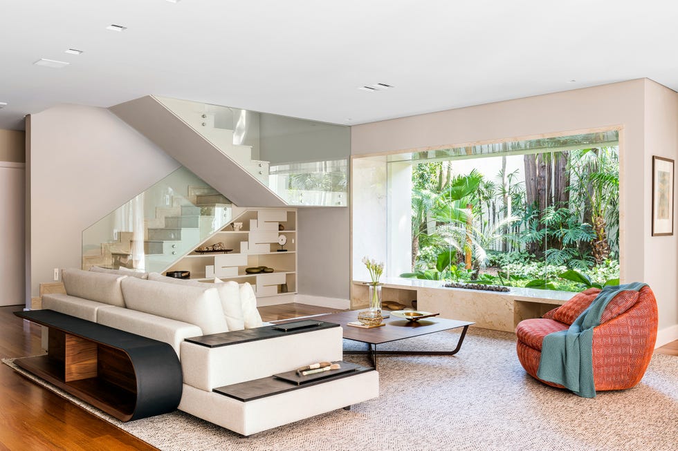 salón con vistas al jardín y estantería bajo la escalera