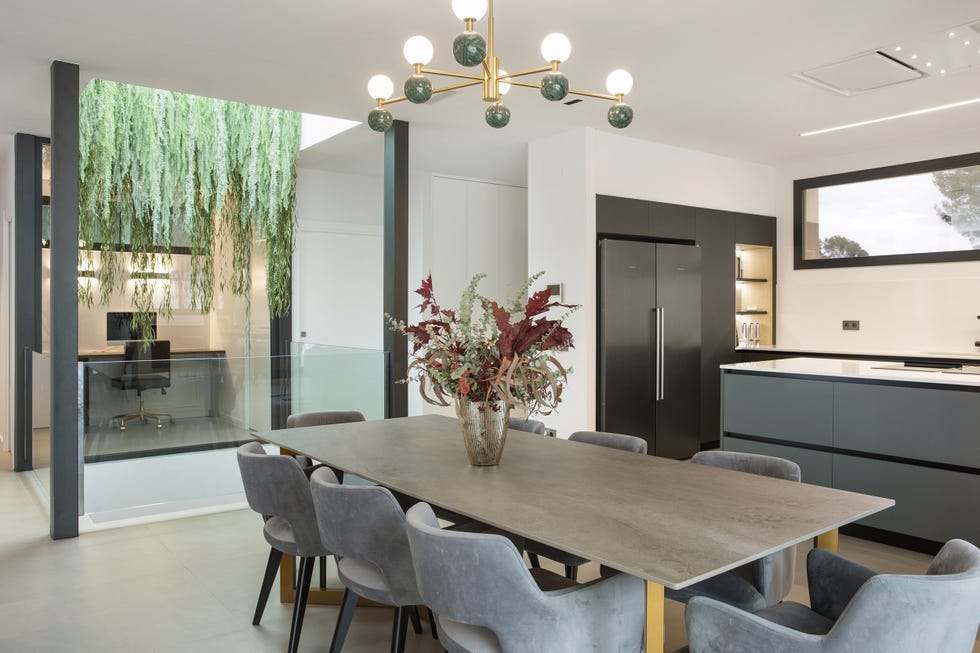 mesa de comedor moderna y alargada con sillas de terciopelo gris junto a la cocina