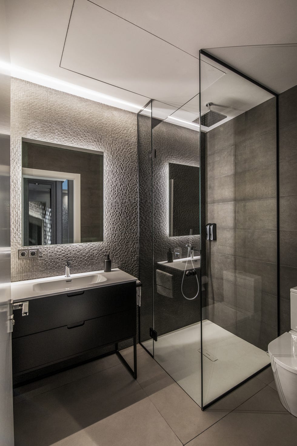 baño con ducha a ras de suelo y mueble de lavabo negro