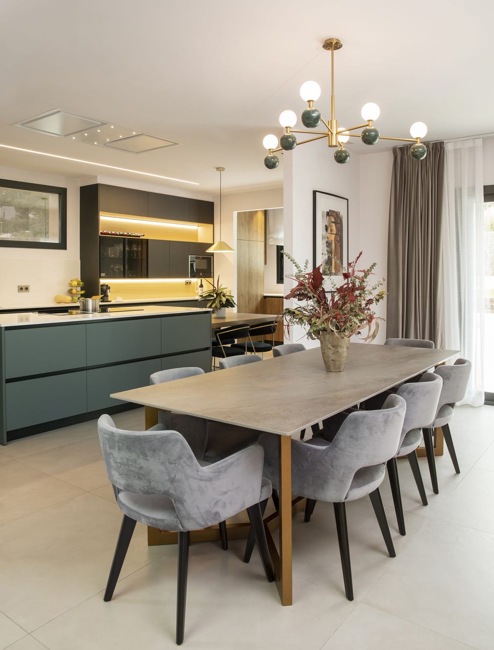 mesa de comedor moderna y alargada con sillas de terciopelo gris junto a la cocina