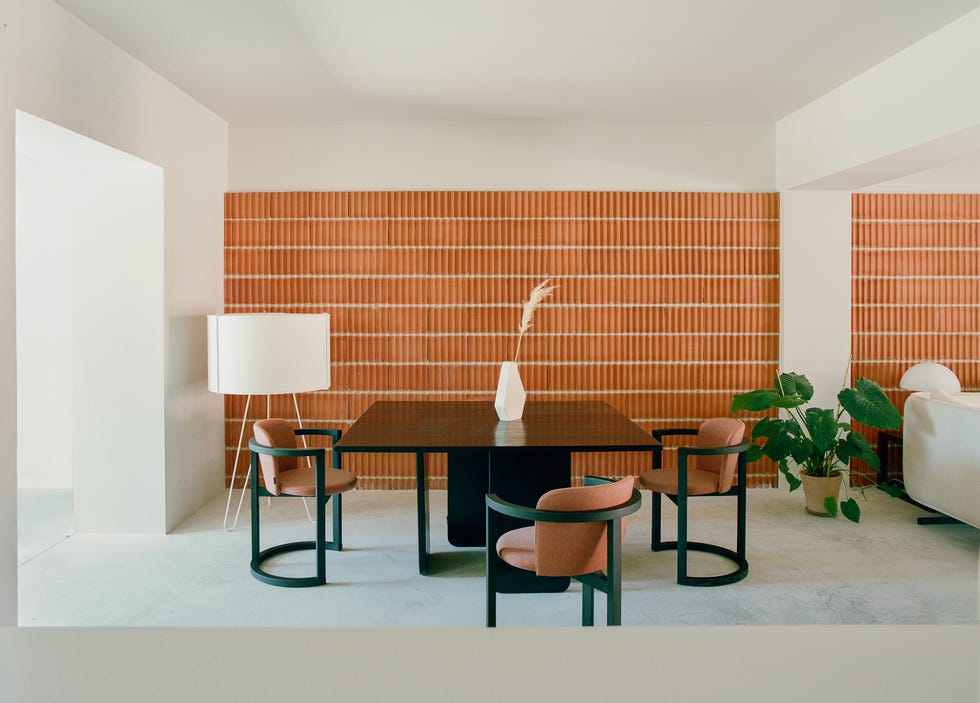 comedor con columnas, mesa y sillas negras de diseño moderno y pared de ladrillo visto
