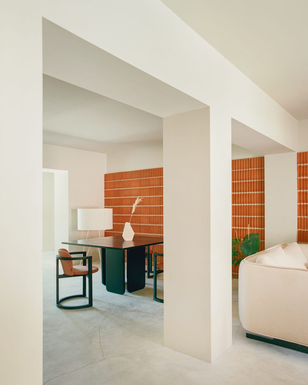 comedor con columnas, mesa y sillas negras de diseño moderno y pared de ladrillo visto