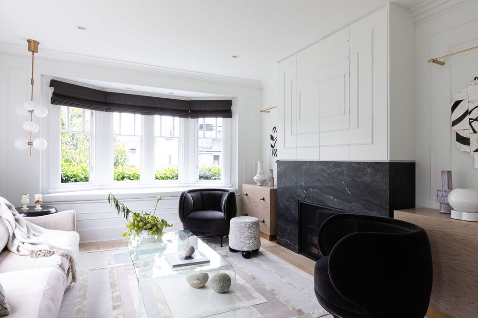 salón decorado en blanco y negro con chimenea de mármol negro y dos butacas de terciopelo negro