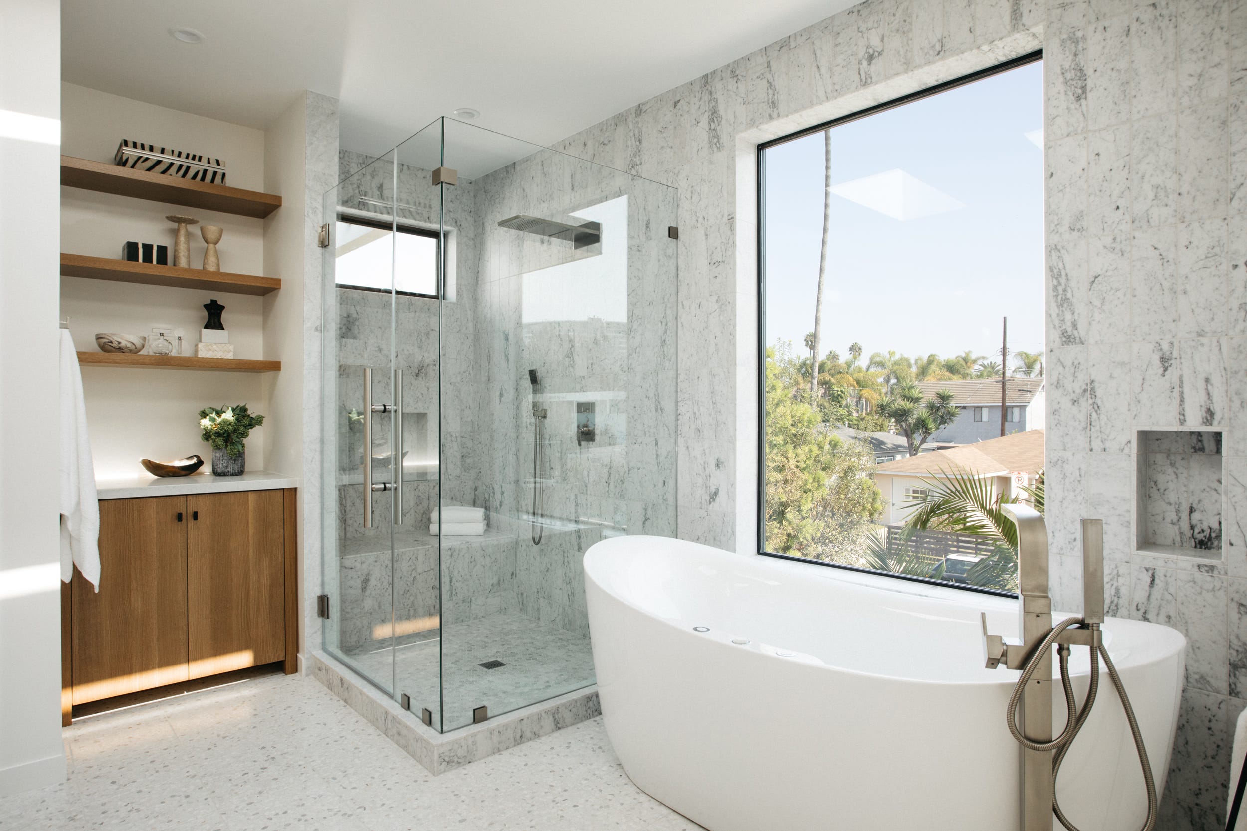 baño revestido con mármol con cabina de ducha y bañera exenta