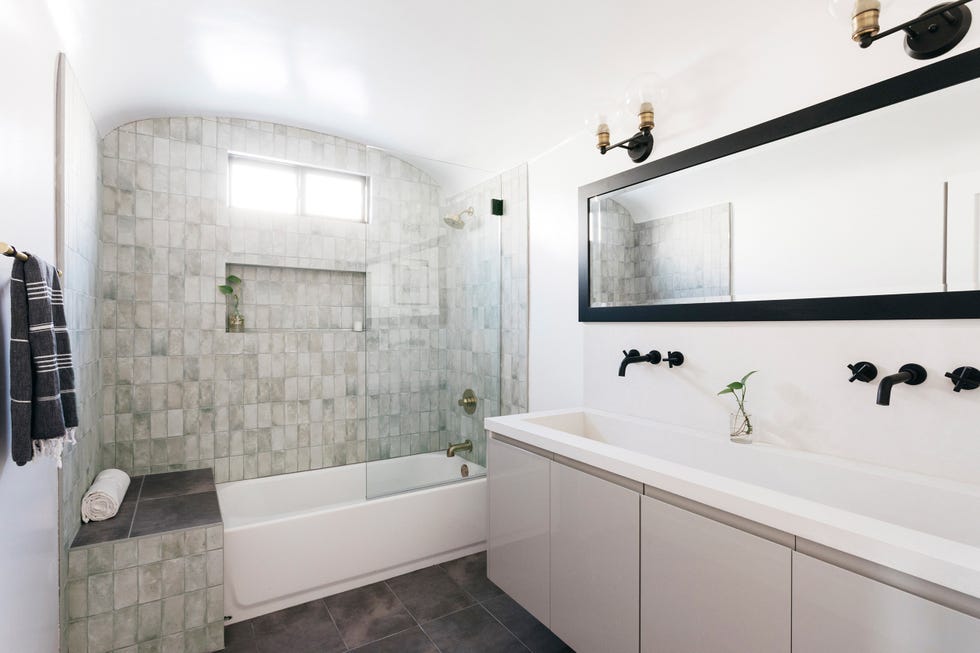 baño con bañera, azulejos grises, y mueble suspendido bajo lavabo