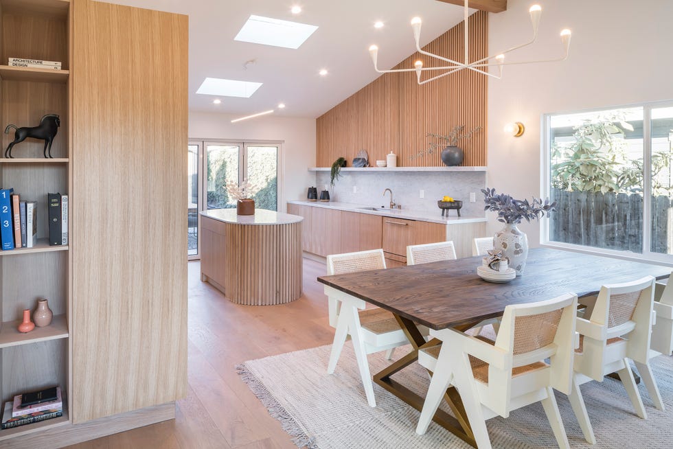 cocina abierta con muebles de madera e isla central ovalada con encimera de mármol