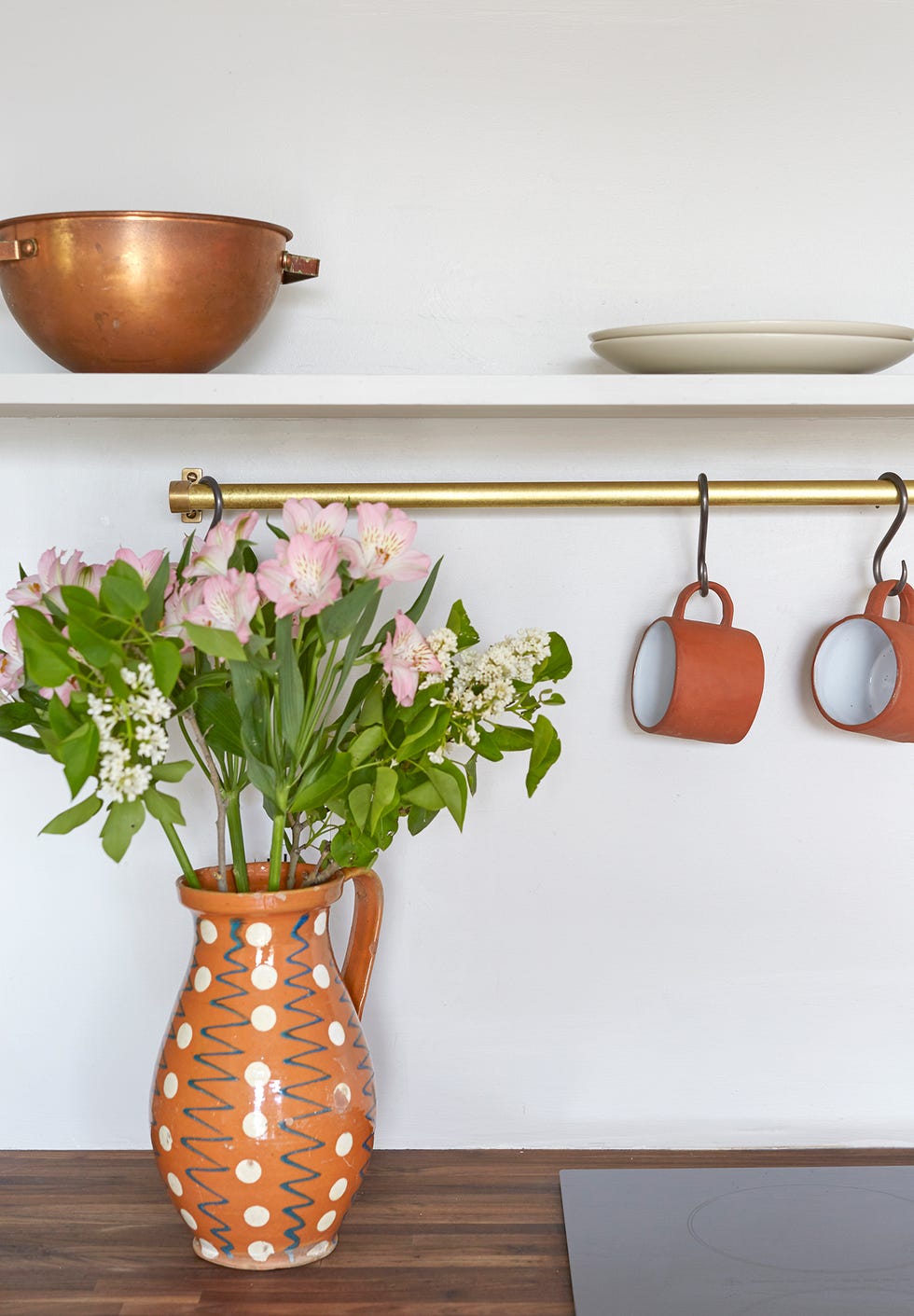 encimera de madera decorada con un jarrón de cerámica con flores