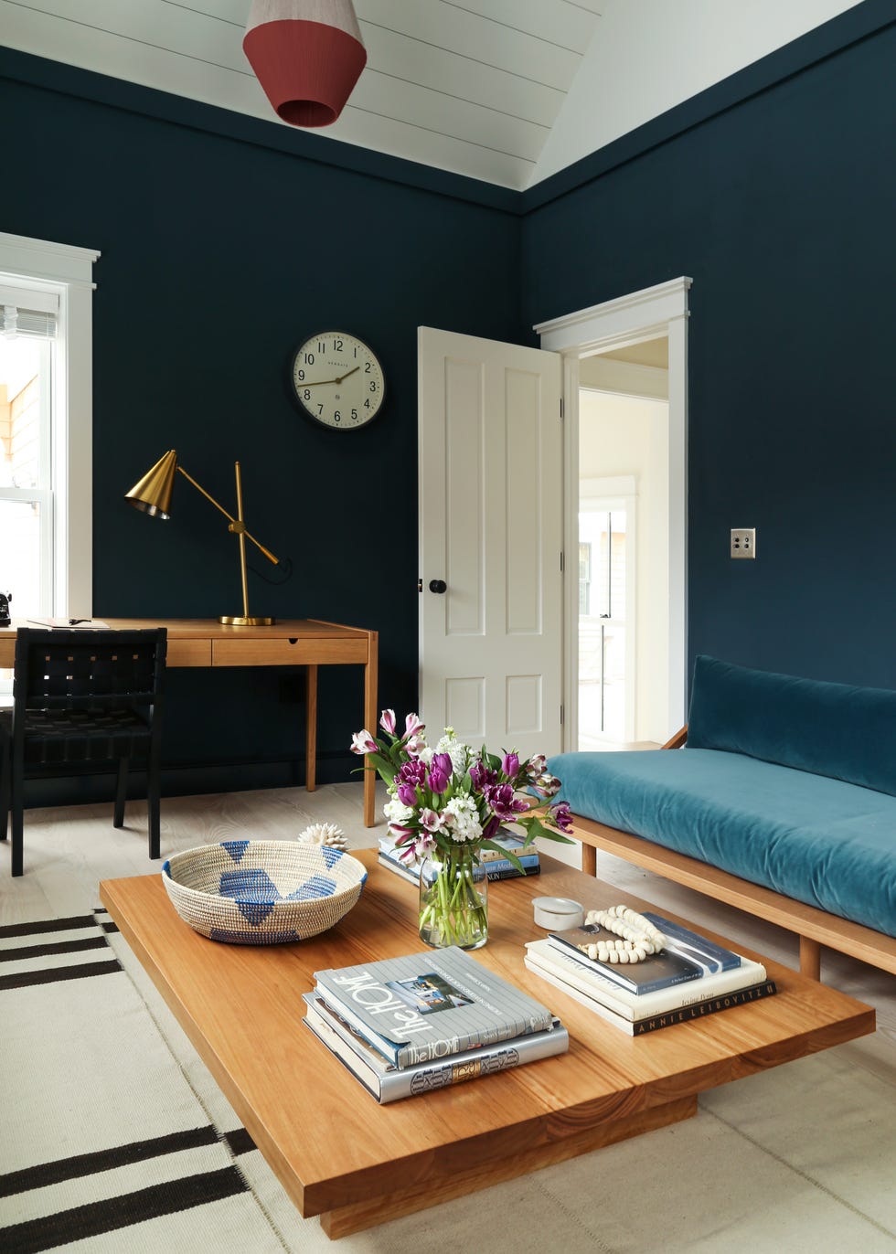 salón con despacho decorado en azul con mesa de centro de madera y sofá de terciopelo