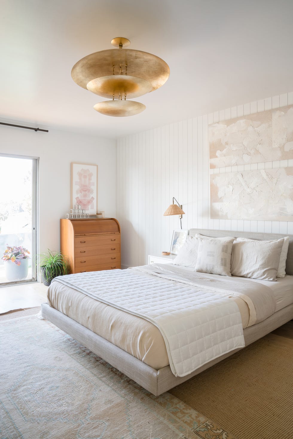 dormitorio decorado en beige con pared de lamas de madera en el cabecero
