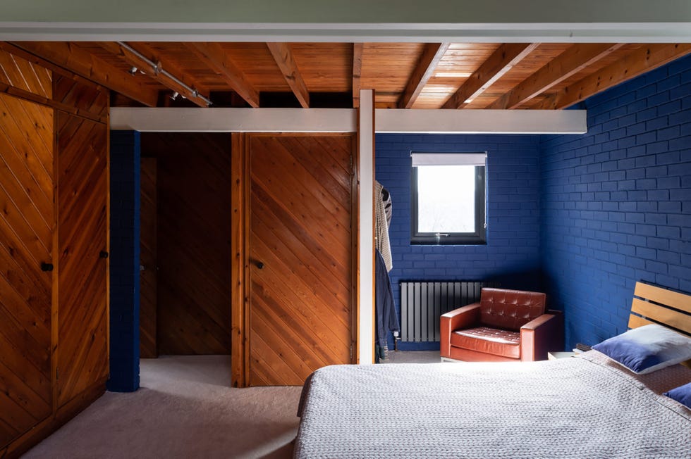 dormitorio con pared de ladrillos azules y puertas, armarios y techo de madera