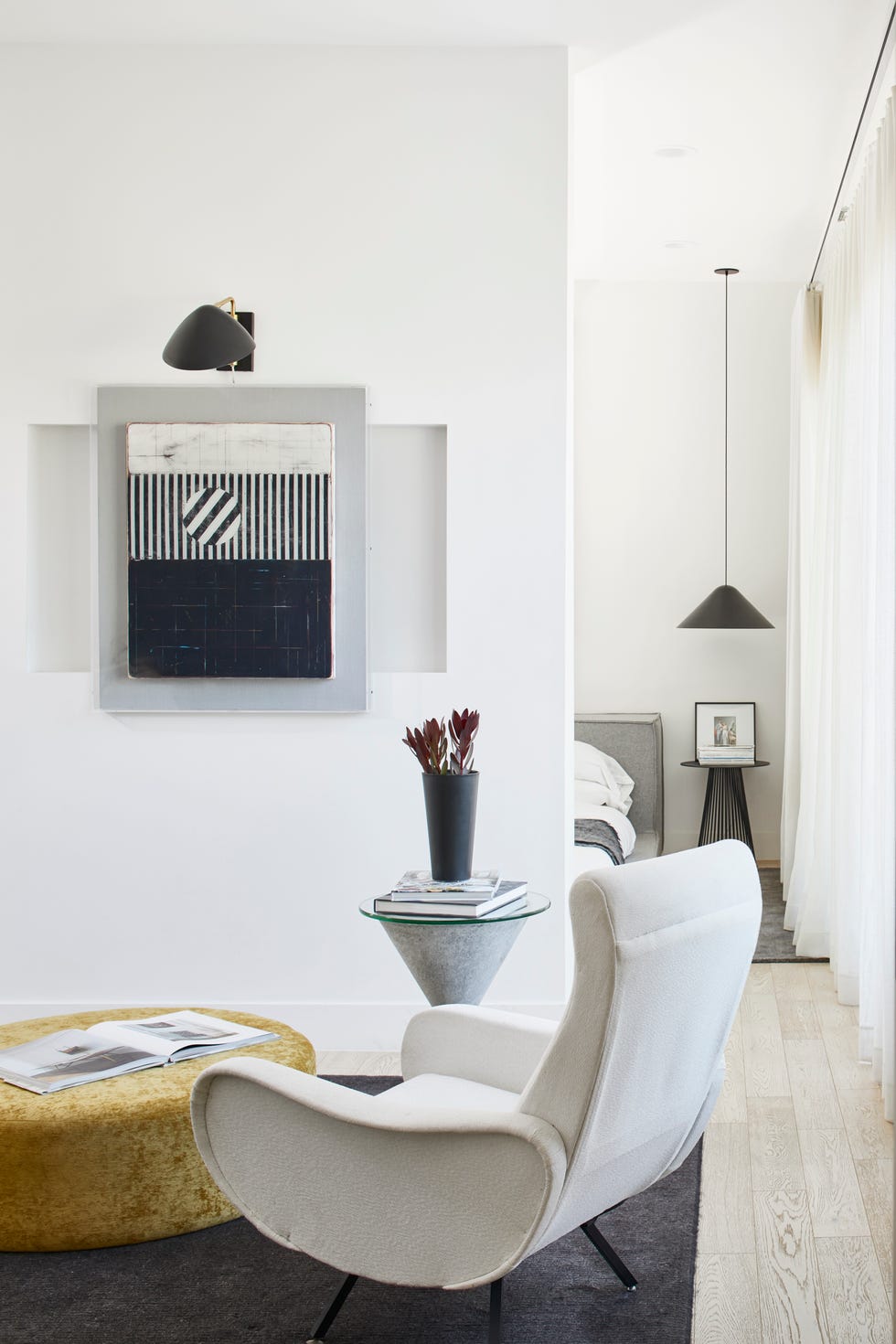 sala de estar con silla de diseño mid century en color blanco y puf de terciopelo mostaza