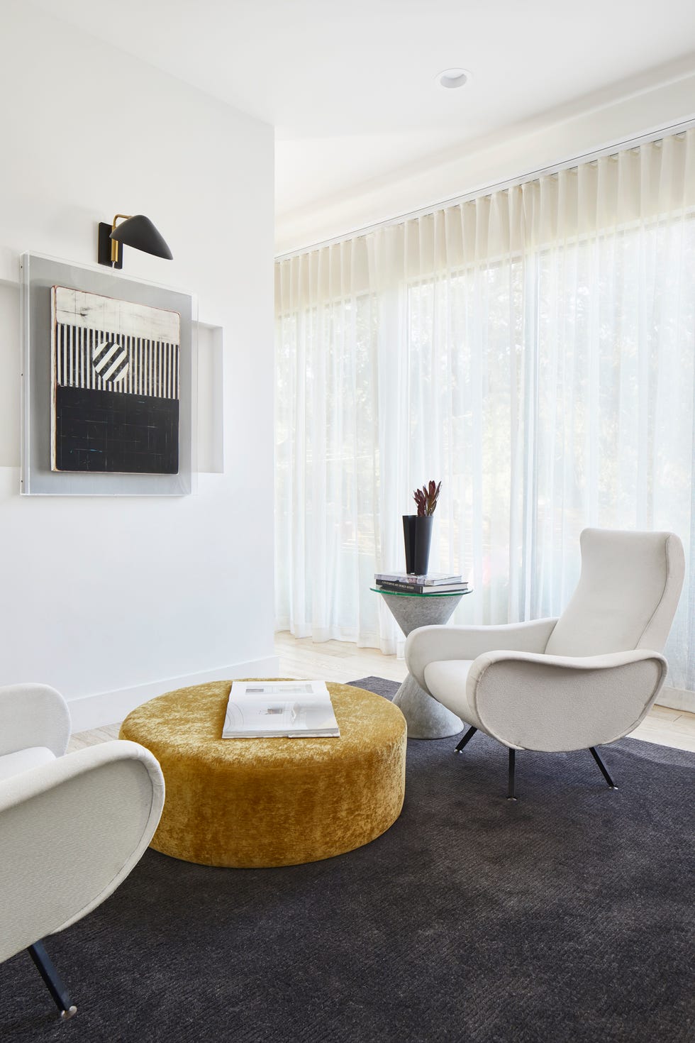 sala de estar con sillas de diseño mid century en color blanco y puf de terciopelo mostaza