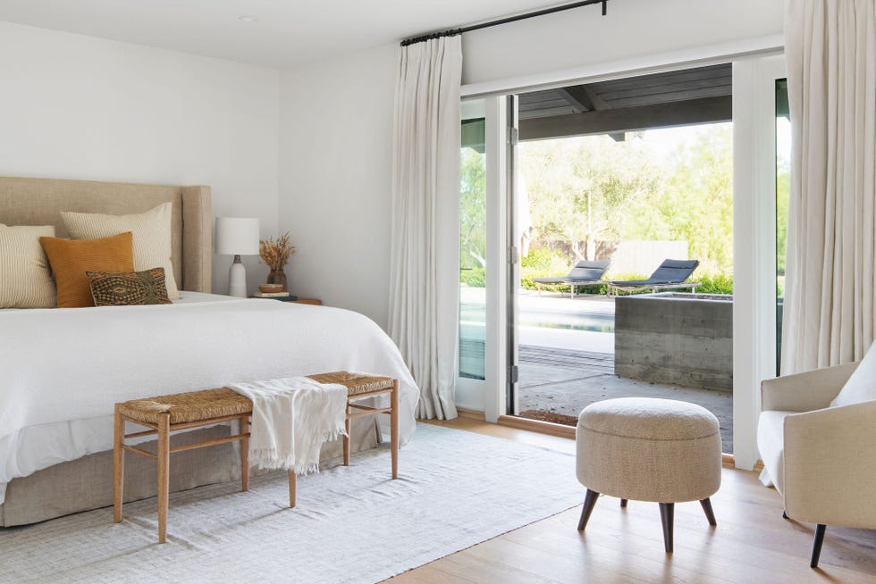 dormitorio de estilo boho con cabecero beige y banco de ratán