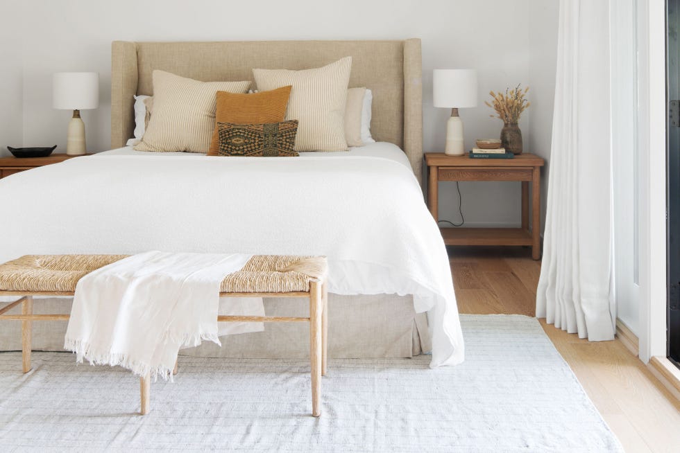 dormitorio de estilo boho con cabecero beige y banco de ratán