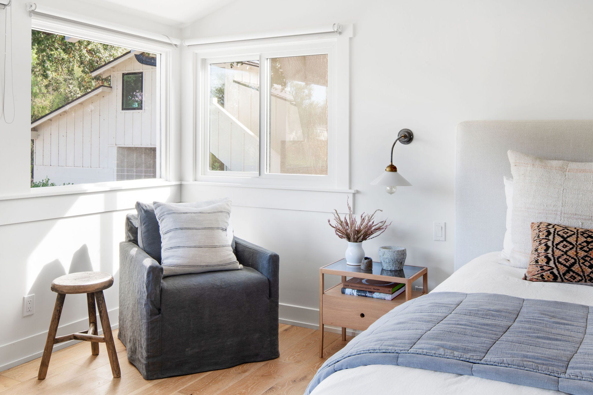 dormitorio con sillón de lino y taburete de madera