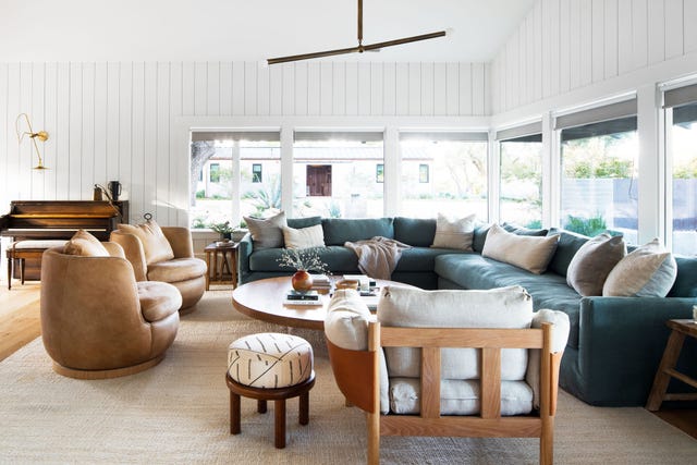 salón con sofá rinconera azul, butacas de piel y mesa de centro de madera