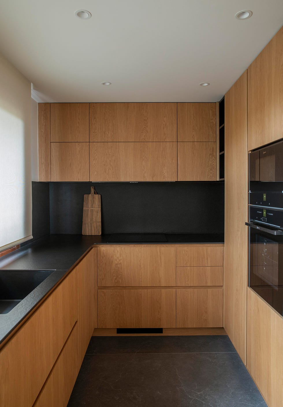 cocina con frentes lisos de madera y encimera negra