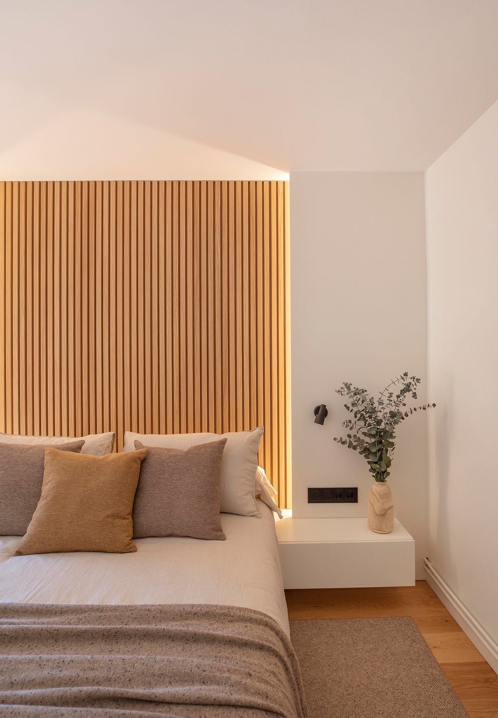 dormitorio con cabecero de listones de madera y mesitas blancas voladas