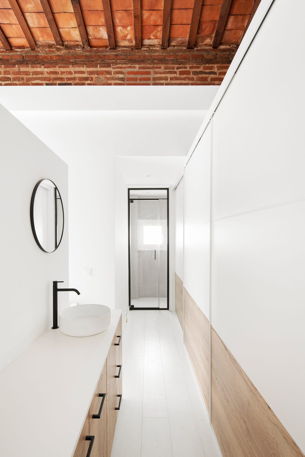 baño con mueble de madera, tiradores y detalles de metal negro y encimera blanca