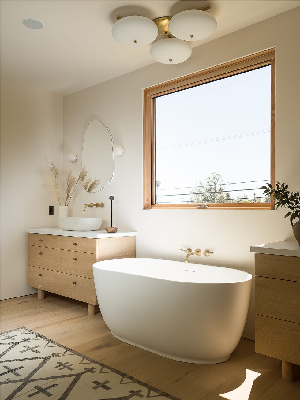 baño con muebles de madera en color claro y bañera exenta de diseño moderno en blanco