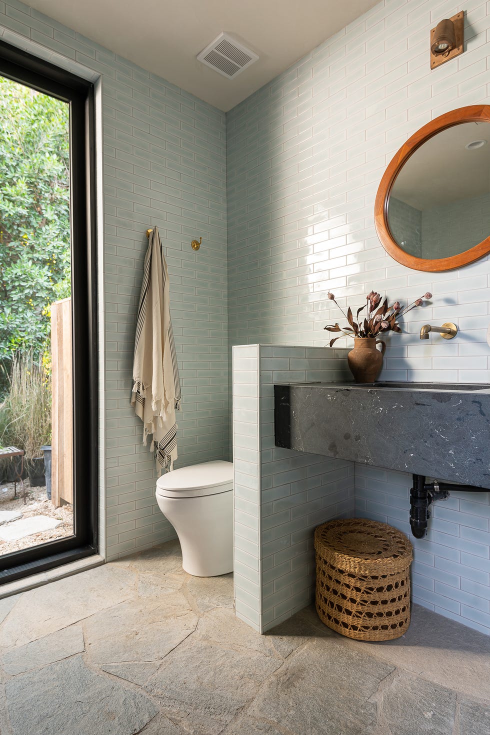 baño con azulejos tipo metro azules y mueble volado de mármol negro