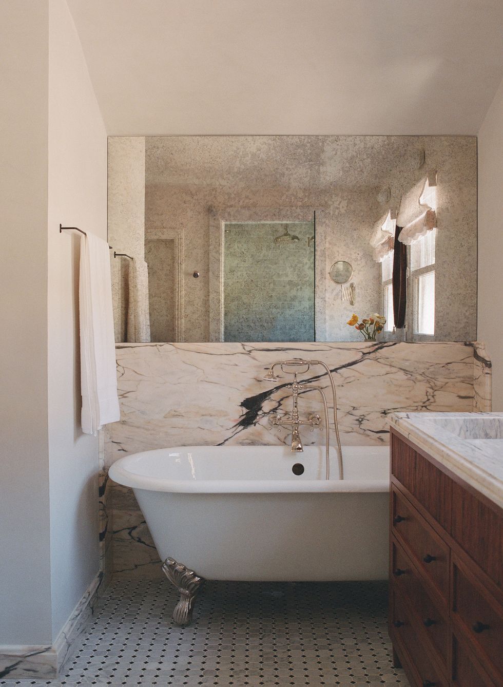 baño con bañera con patas y revestimiento de mármol en las paredes