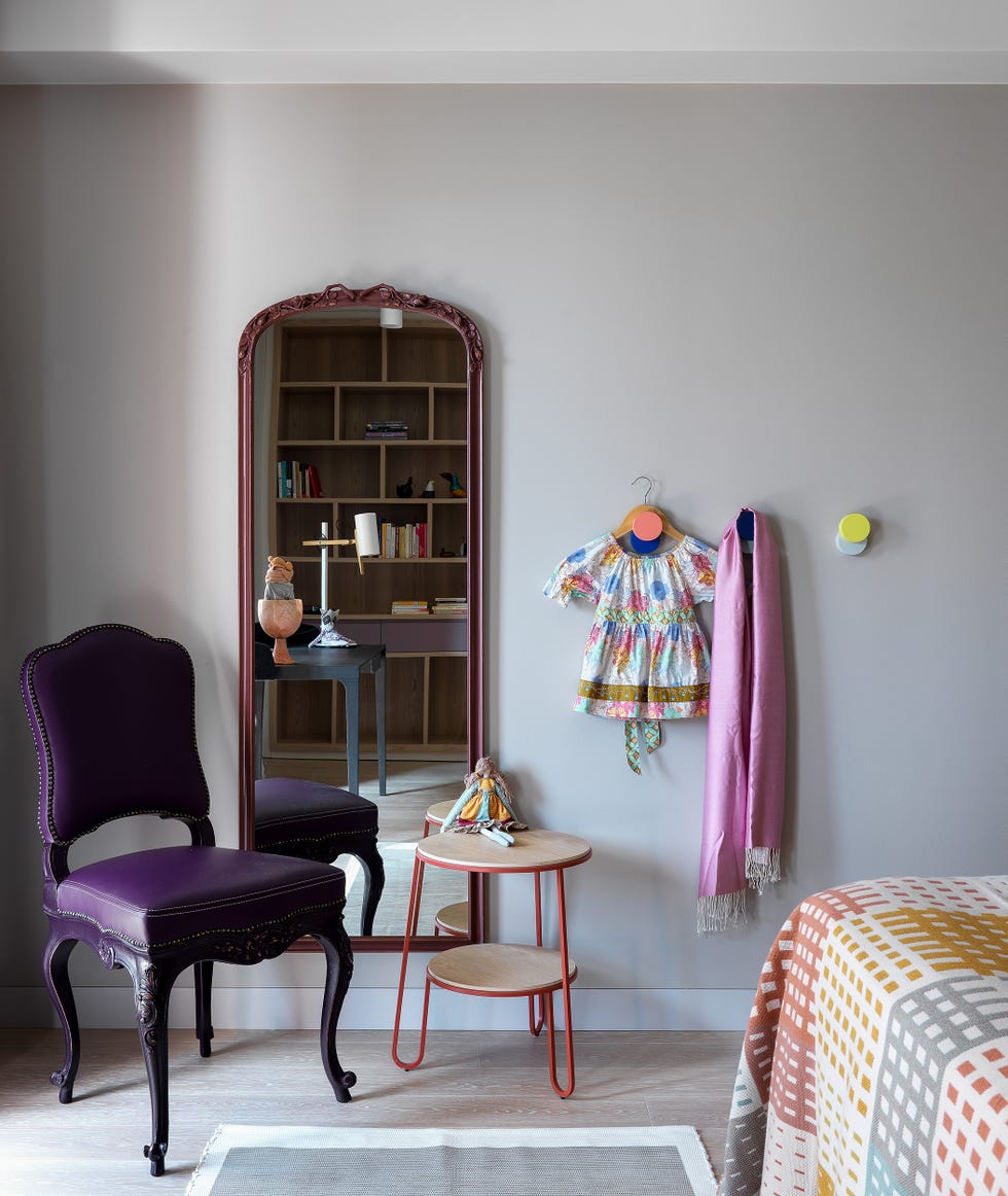 butaca estilo victoriano en color morado junto a espejo de pie y mesa auxiliar