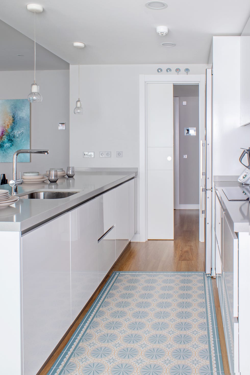 cocina abierta con puertas sin tiradores de acabado lacado blanco y alfombra vinílica