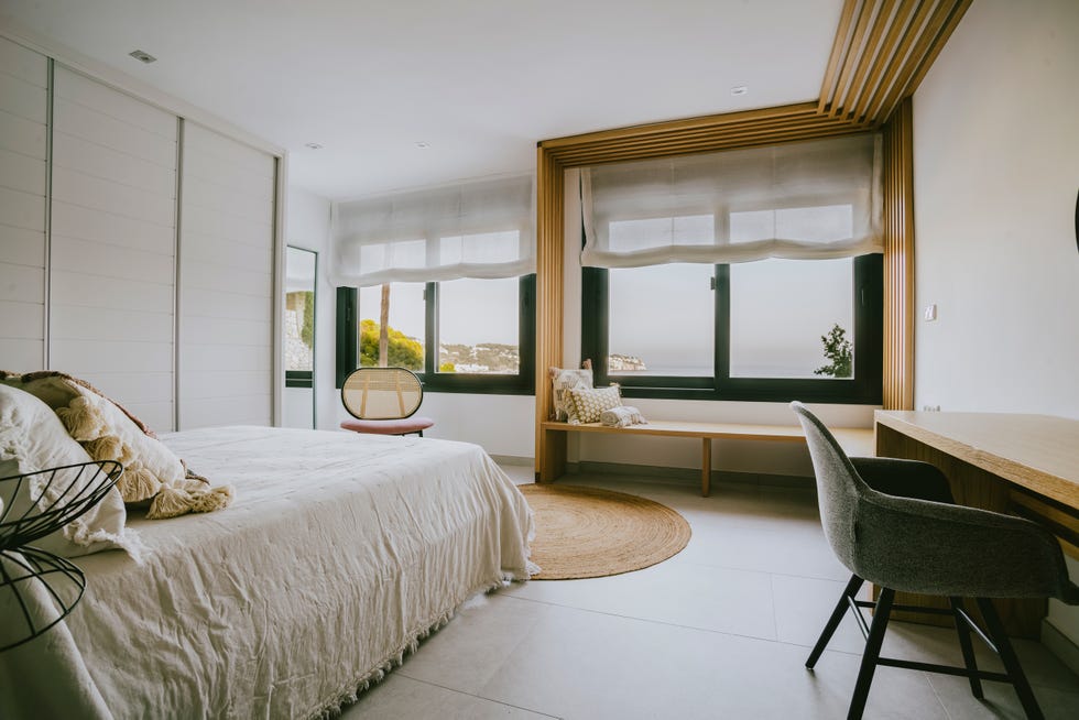 dormitorio con escritorio y banco de madera bajo la ventana