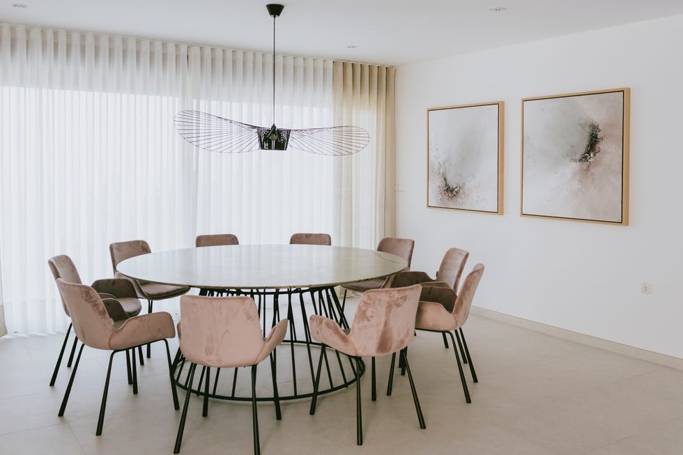 comedor con mesa redonda de mármol y acero y sillas de terciopelo rosa
