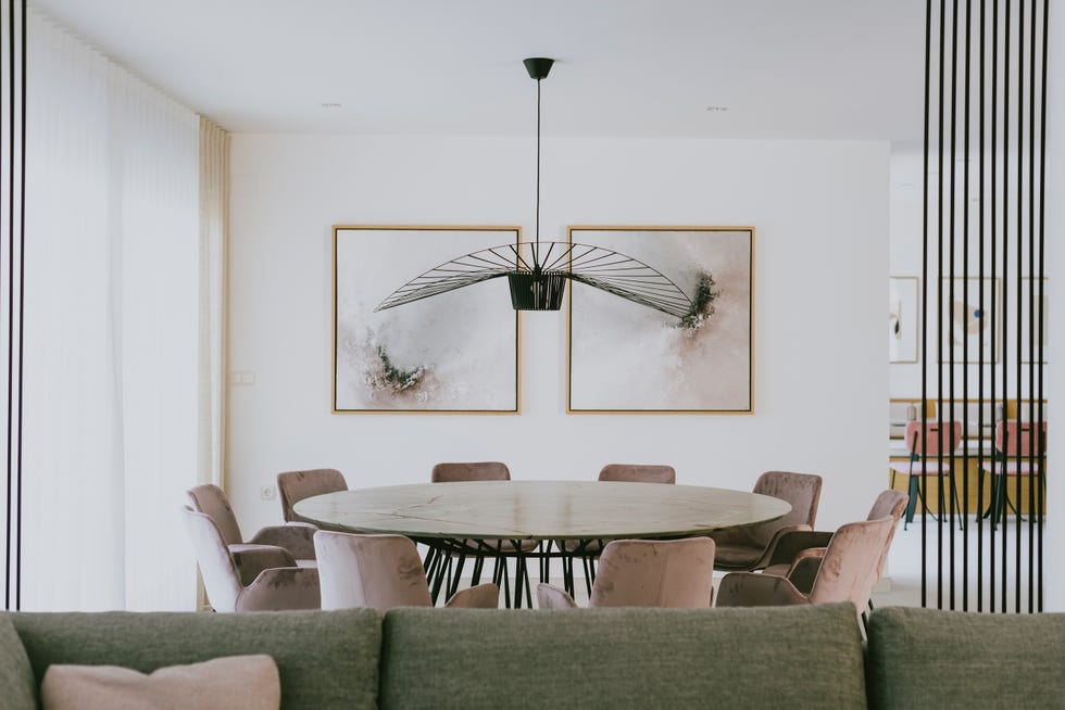 comedor con mesa redonda de mármol y acero y sillas de terciopelo rosa